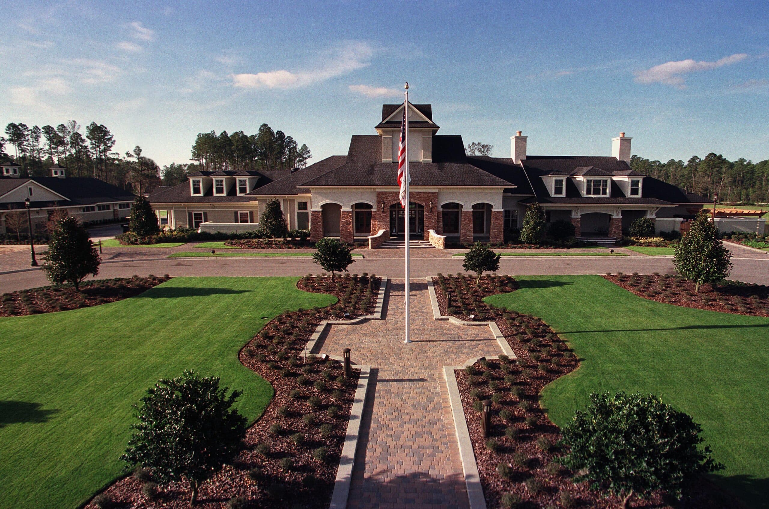 Aerial view of the St. Johns Golf & Country Club clubhouse with its glass conservatory atrium, pool, and adjacent championship golf course in St. Augustine, Florida